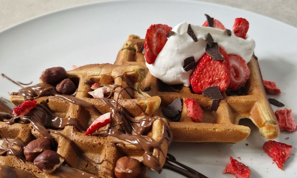 Fluffige vegane Proteinwaffeln mit Schokolade, Sahne und Erdbeeren