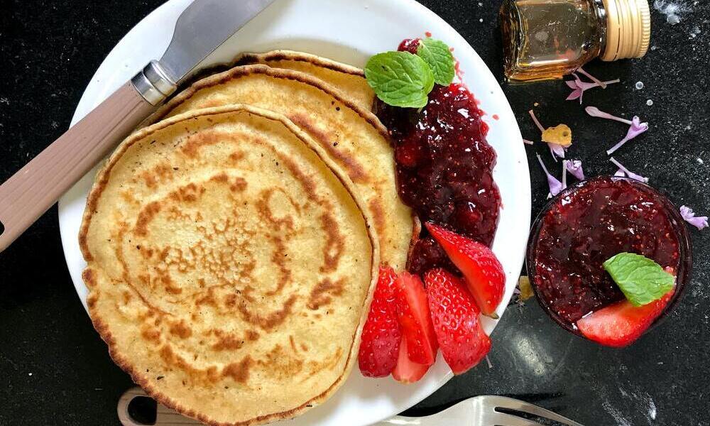 Vegane Pancakes mit Beerenmarmelade und Früchten auf einem Teller angerichtet