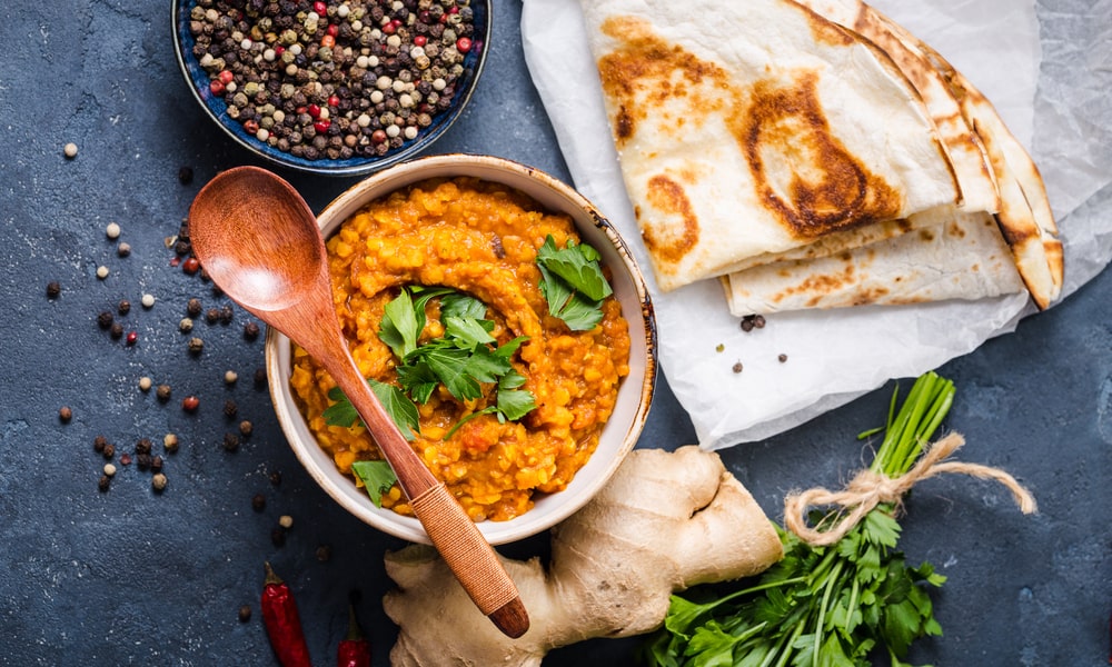 Linsen Dal mit roten Linsen, angerichtet mit Ingwer, Petersilie und Naan