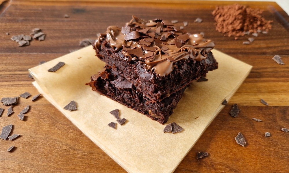 Vegane Protein Brownies auf einem Holzbrett mit Deko