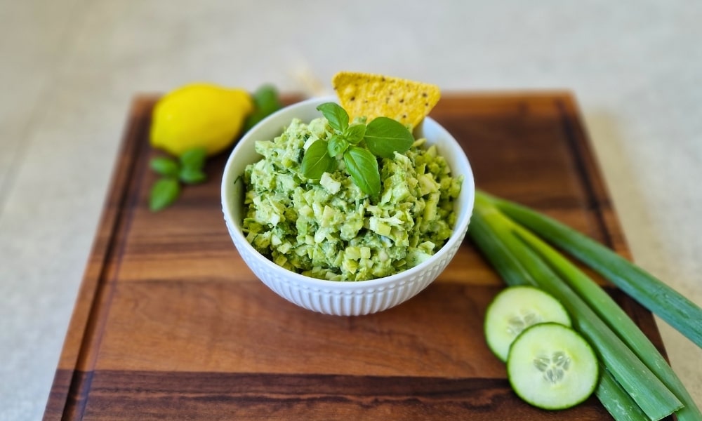Weiße Schale mit frischem, veganem Green Goddess Salat, darum herum die Zutaten