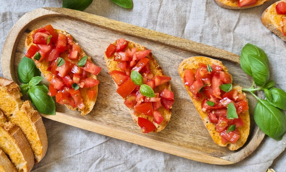 Bruschetta auf einem Holztablett mit frischem Basilikum