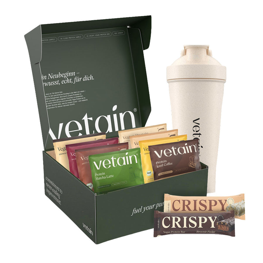 Opened dark green Vetain sample box with protein sample sachets in various flavors, a cream-colored shaker, and two Crispy protein bars, isolated against a white background.