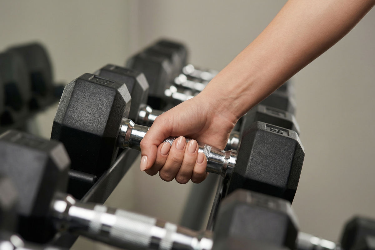 Eine Frauenhand greift eine von mehreren Hanteln