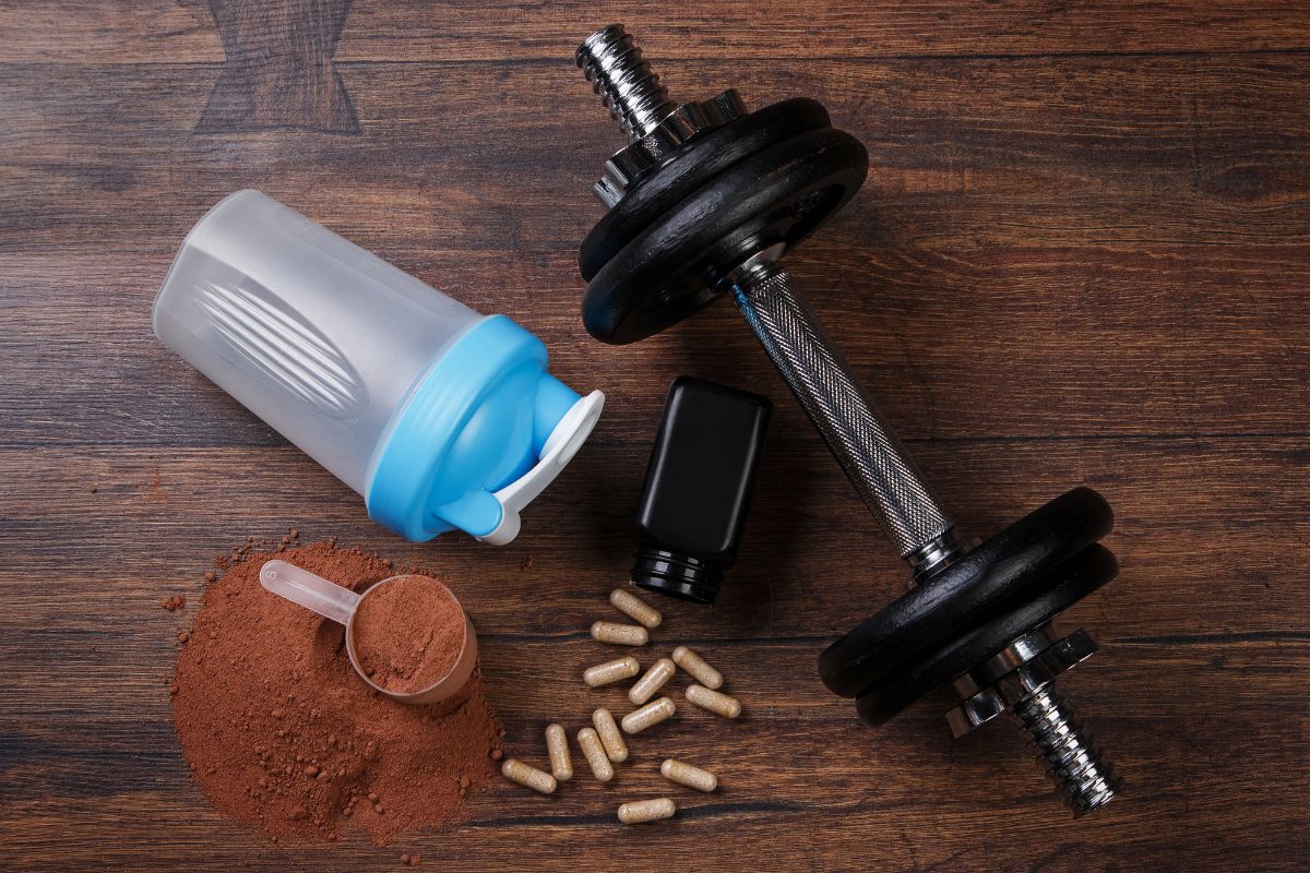 Hantel, Shaker und Supplements auf Holzboden