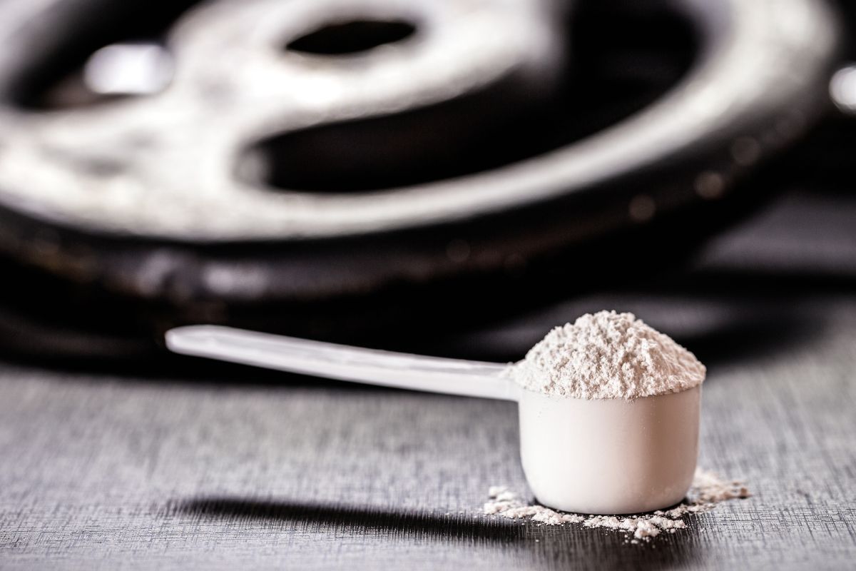 Creatin in einem Scoop, im Hintergrund eine Hantel