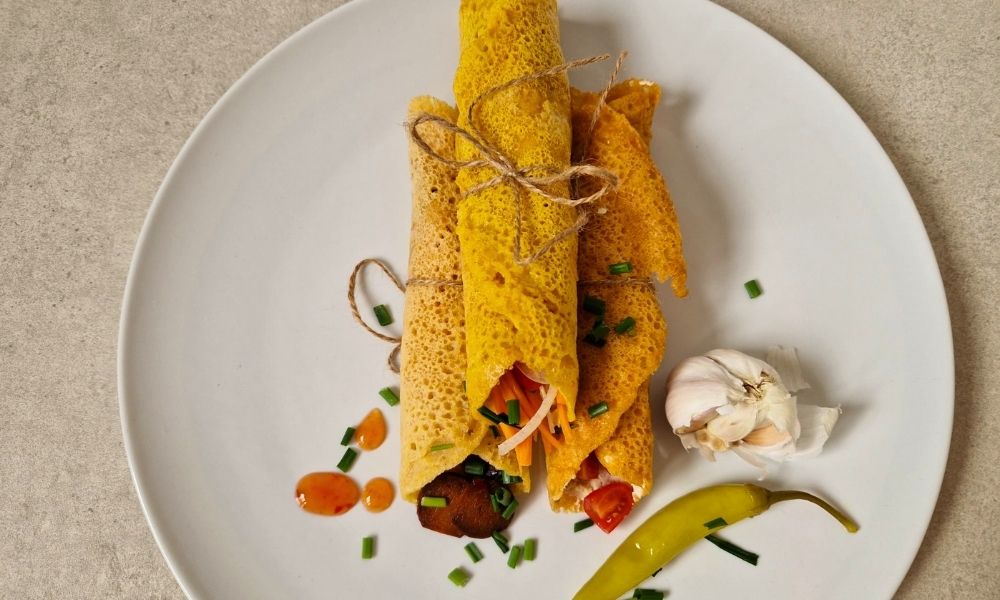 Drei Protein Wraps mit verschiedenen Füllungen auf einem weißen Teller mit Deko