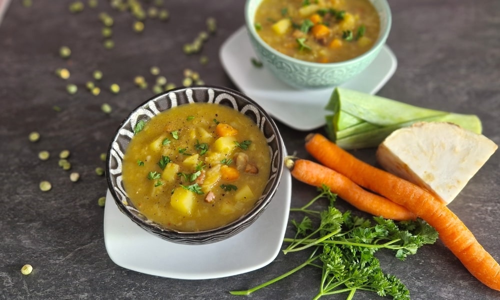 2 Schalen mit veganer Erbsensuppe, einzelne Zutaten als Deko drum herum