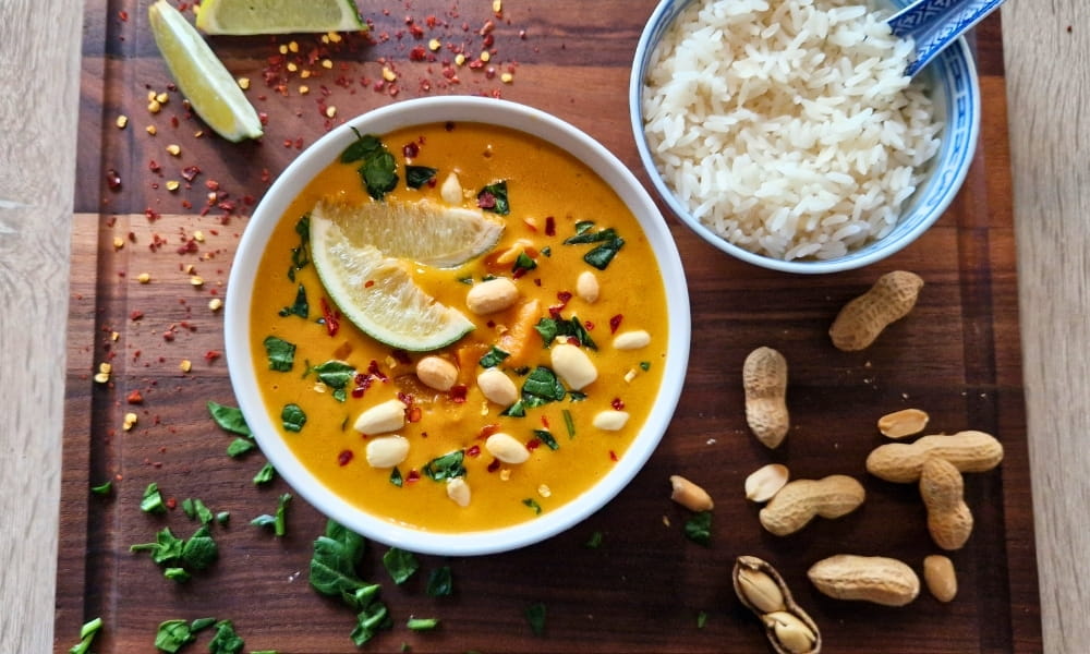 Erdnuss Curry mit einer Schüssel Reis und leckeren Toppings