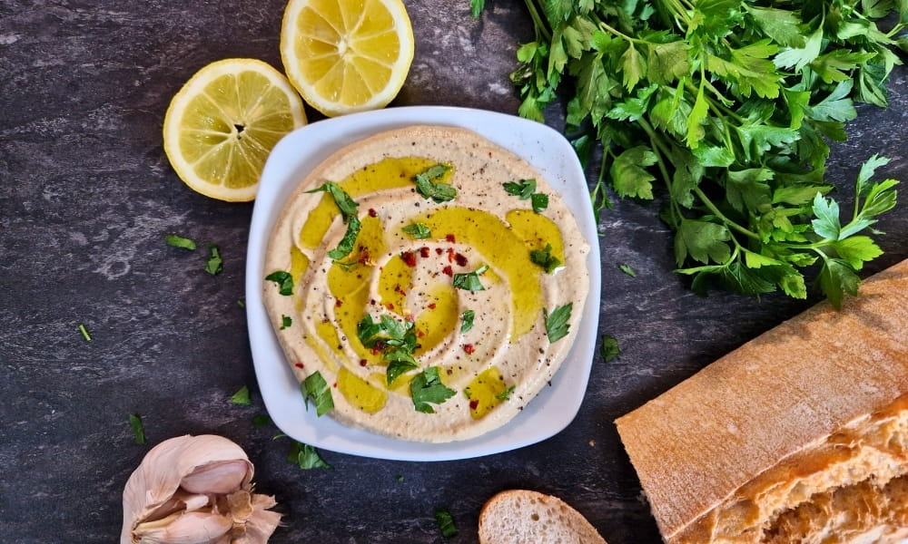 Mutabal auf einem Teller mit frischer Zitrone, Petersilie und Brot