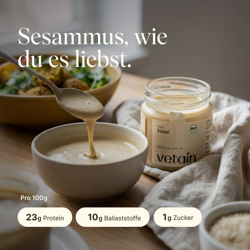 Sesamus, wie du es liebst. Vetains Tahini mit 23g Protein, 10g Ballaststoffen und 1g Zucker pro 100g. Das Bild zeigt das Offene Tahiniglas, daneben eine mit Tahini gefüllte Schüssel und einem Löffel, von welchem das Tahini tropft.