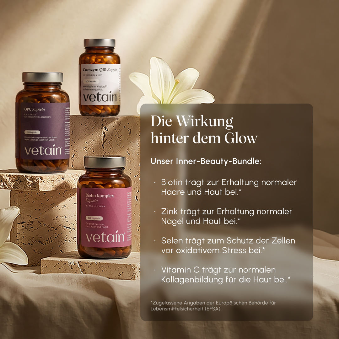Vetain Inner Beauty Bundle – OPC capsules, Coenzyme Q10 capsules, and Biotin Complex capsules on stone pedestals with a white lily flower. Text overlay "The effect behind the glow": Biotin for hair and skin, zinc for nails and skin, selenium against oxidative stress, vitamin C for collagen formation (EFSA-approved information)