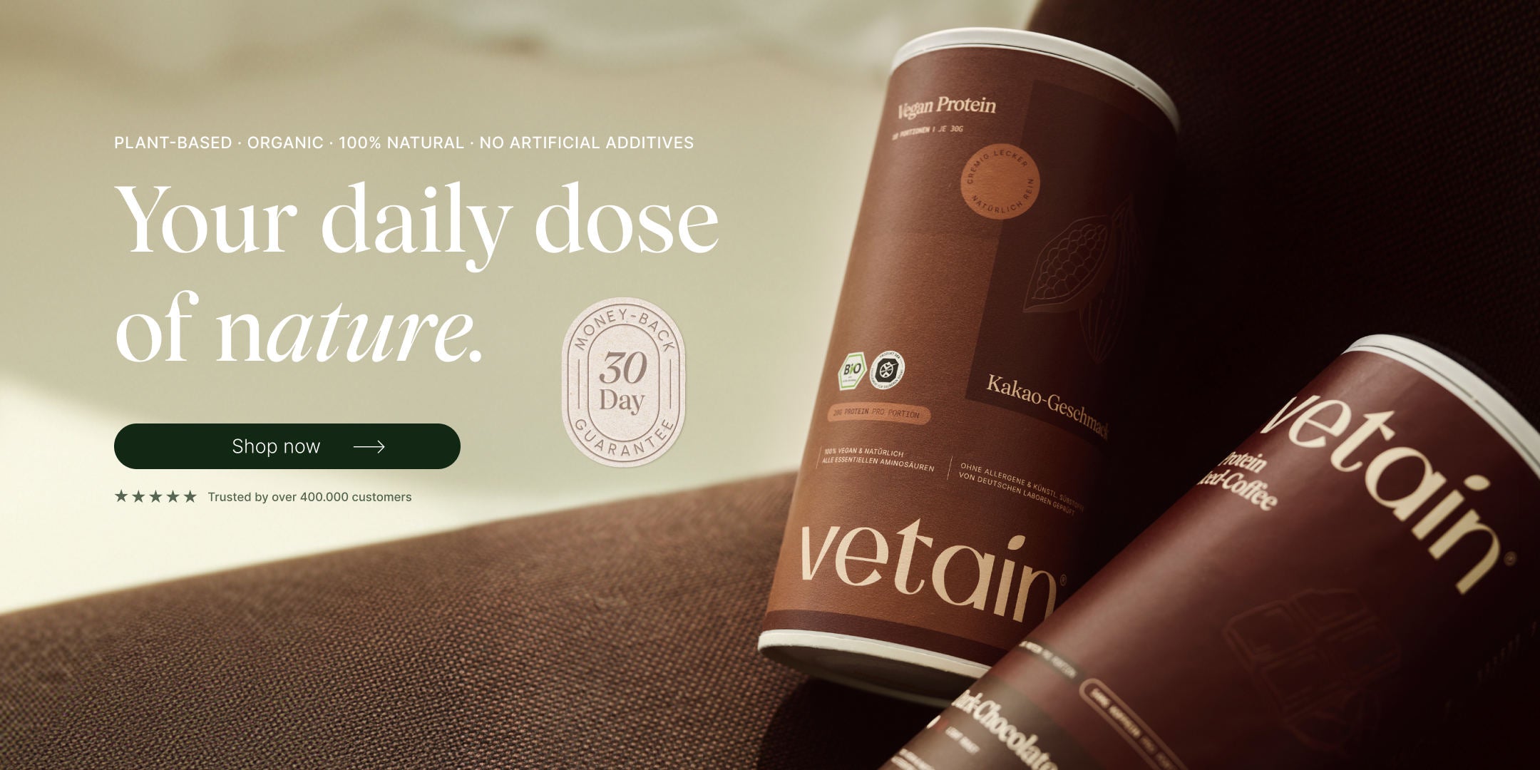 Vetain Vegan Protein hero banner with two tubs (cocoa and iced-coffee flavour) on brown fabric. Headline "Your daily dose of nature." with "Shop now" button, 30-day money-back seal and "Trusted by over 400,000 customers".