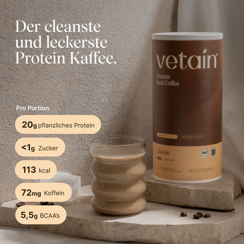 Vetain Protein Iced Coffee Classic (Bio) neben einem Glas kaltem Protein-Kaffee auf Steinpodest mit Kaffeebohnen. Text: „Der cleanste und leckerste Protein Kaffee.“ Nährwerte pro Portion: 20g pflanzliches Protein, <1g Zucker, 113 kcal, 72mg Koffein, 5,5g BCAAs.