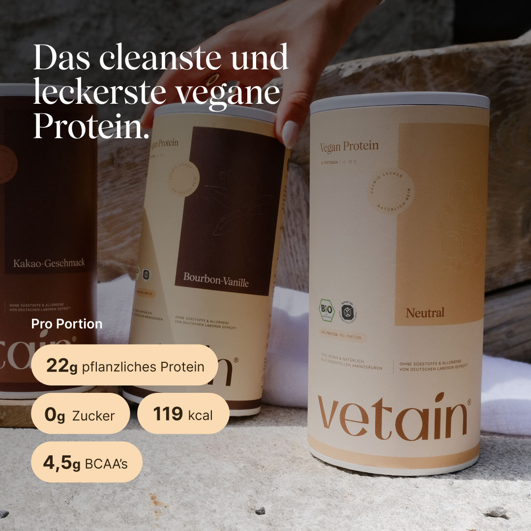 Three vetain vegan protein tubs (cocoa flavor, bourbon vanilla, and unflavored) on a stone surface; a hand reaches for the middle tub. The unflavored tub is in the foreground. Text: “The cleanest and tastiest vegan protein.” Per serving: 22 g plant-based protein, 0 g sugar, 119 kcal, 4.5 g BCAAs.