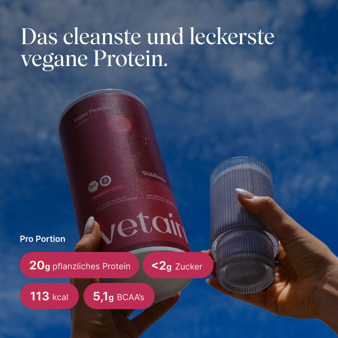 Zwei Hände halten die vetain Vegan Protein Dose (Waldbeere) und ein geripptes Glas mit violettem Proteinshake vor blauem Himmel. Text: „Das cleanste und leckerste vegane Protein." Pro Portion: 20g pflanzliches Protein, <2g Zucker, 113 kcal, 5,1g BCAAs.