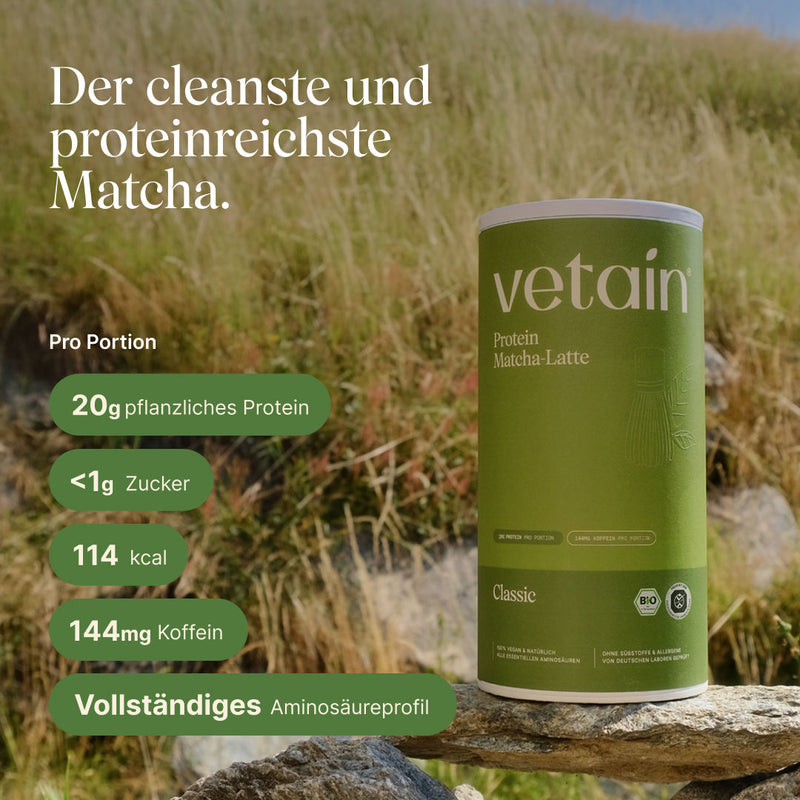 Dose vetain Protein Matcha-Latte in the Classic flavor on a stone in front of a sunny grassland. Headline: 'The cleanest and most protein-rich Matcha.' Information per serving: 20 g plant-based protein, under 1 g sugar, 114 kcal, 144 mg caffeine, complete amino acid profile.