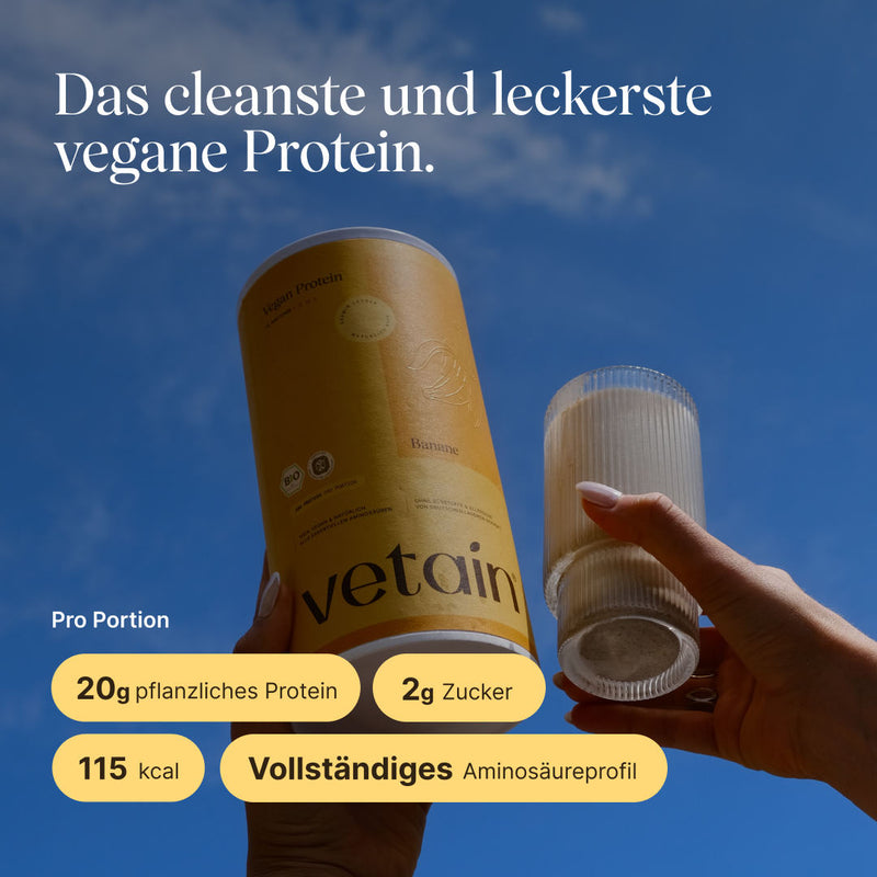 Hand holding a can of vetain Vegan Protein in banana flavor against a blue sky, next to a glass with a prepared protein shake. Headline: 'The cleanest and tastiest vegan protein.' Per serving: 20 g plant-based protein, 2 g sugar, 115 kcal, complete amino acid profile.