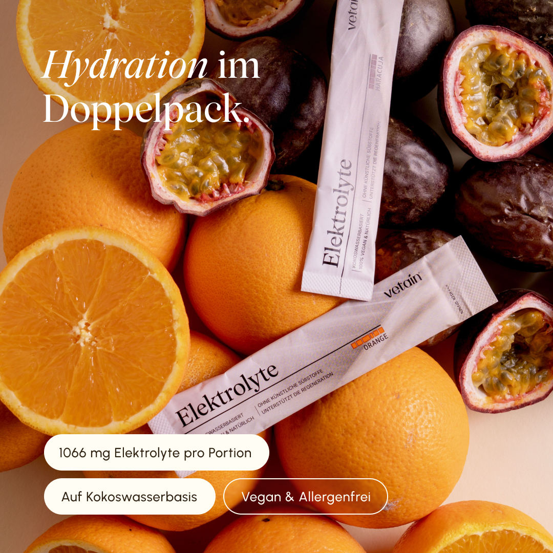 Vetain Elektrolyte-Sticks in den Sorten Orange und Maracuja, arrangiert zwischen frischen Orangen und aufgeschnittenen Passionsfrüchten. Das Bild hebt die natürliche Kokoswasserbasis, 954 mg Elektrolyte pro Portion sowie die veganen und allergenfreien Eigenschaften des Produkts hervor.