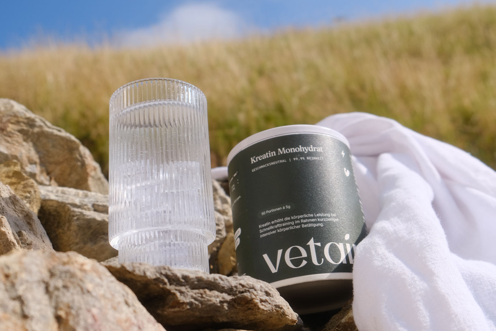 Vetains veganes Kreatin Monohydrat in einer Dose und angerührt als Getränk in einem Glas in der Natur