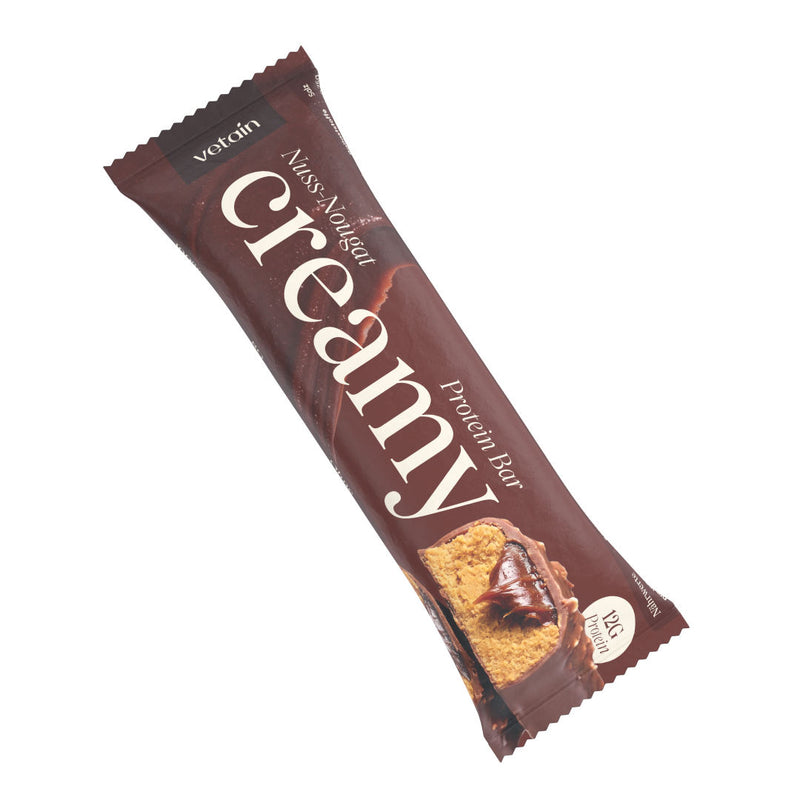 Single individually wrapped nut nougat creamy protein bar lying diagonally against a white background.