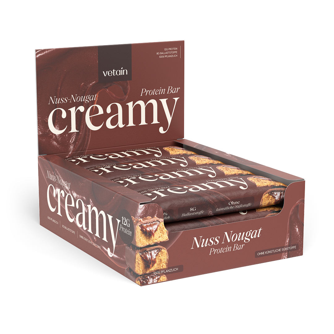 Geöffnete 12er-Displaybox „Nuss-Nougat Creamy Protein Bar" schräg von vorne, mit sichtbaren einzeln verpackten Riegeln, freigestellt vor weißem Hintergrund.