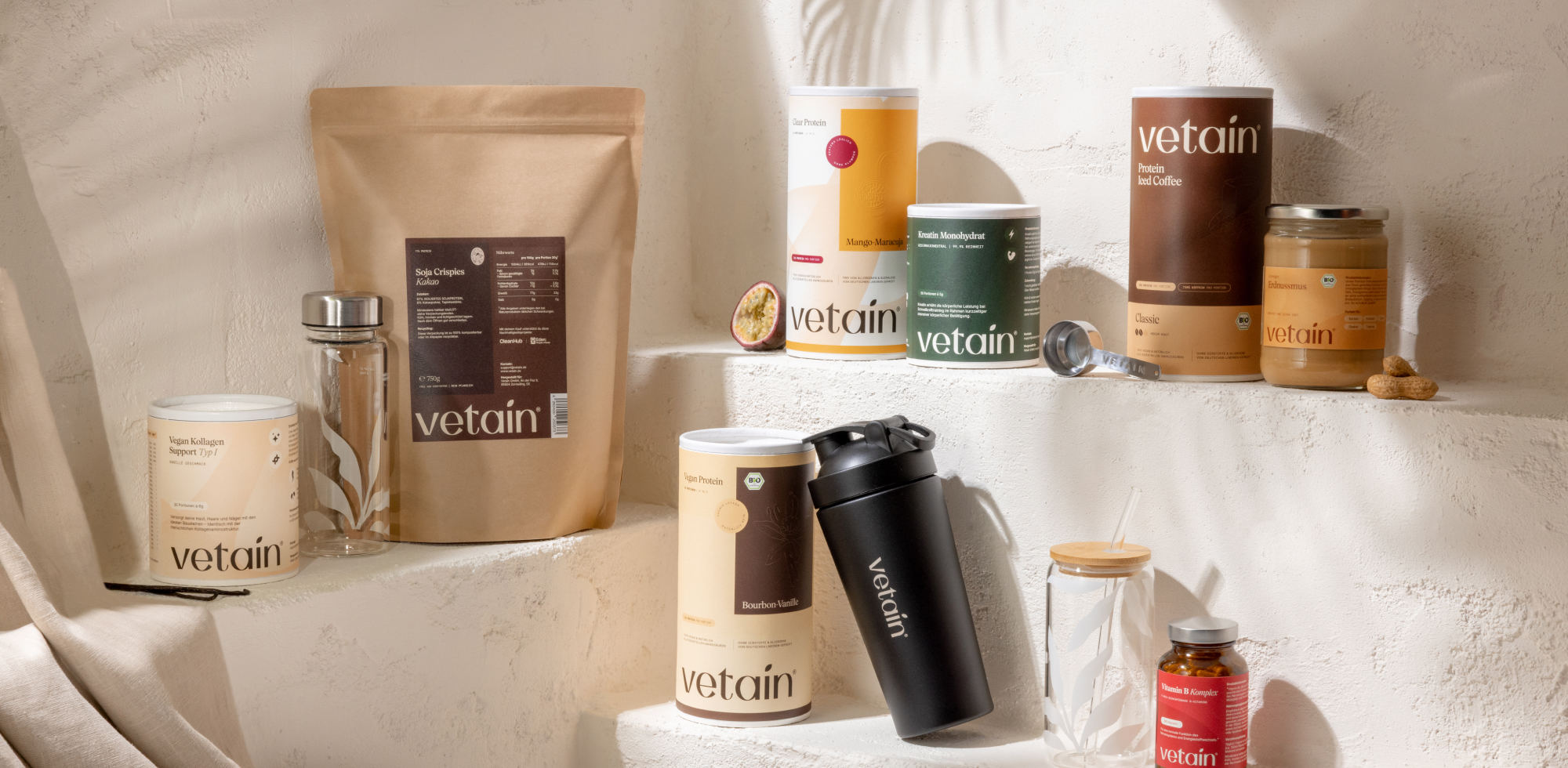 Vetain vielfältige Produktauswahl. Produkte wie Kreatin, veganes Proteinpulver, Shaker oder Trinkflasche auf einer Treppe drappiert