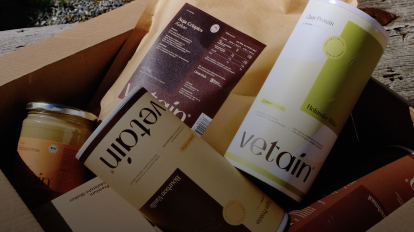 Vetain Proteinpulverdosen und ein Nussmusglas liegen in einem Karton
