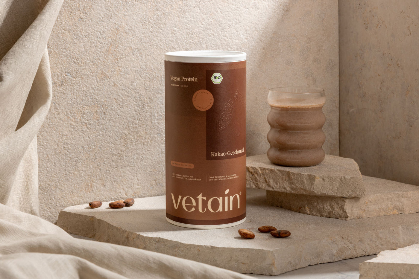 Vetain vegan Protein Geschmack Kakao. In der Dose, daneben ein Glas mit dem Proteinshake darin